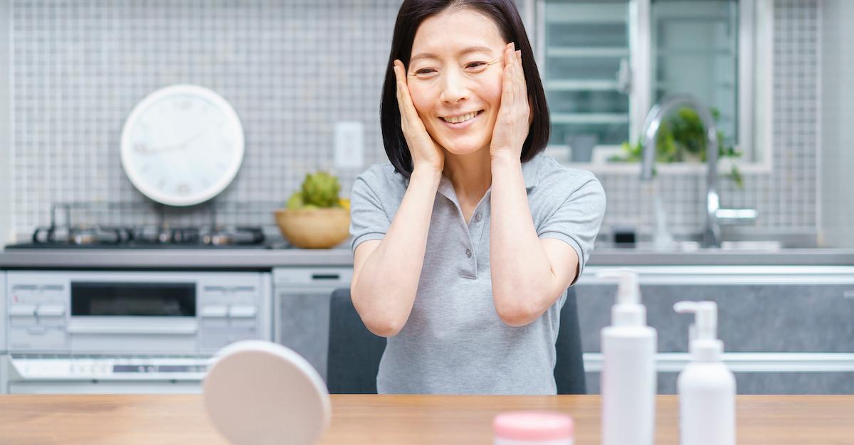 A woman does her skin care routine with a mirror.