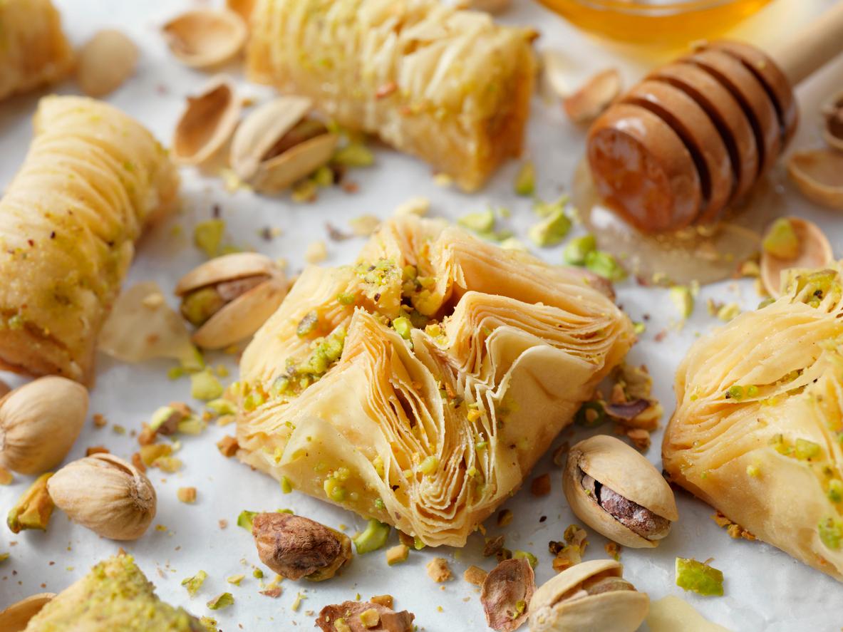 A baklava pastry puff with pistachios is depicted on a baking tray.