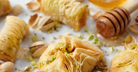 A baklava pastry puff with pistachios is depicted on a baking tray.