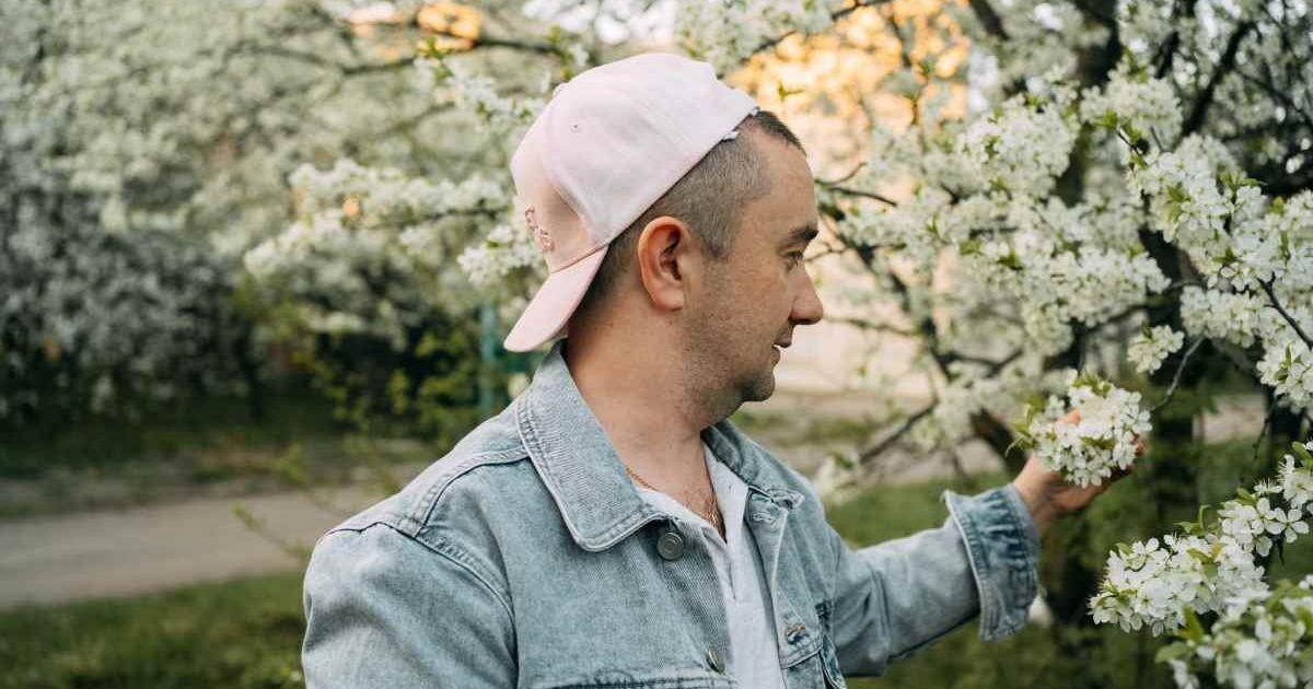 A man admiring a tree with white flowers blooming during springtime. (Representative Cover Image Source: Getty Images | Svetlana Repnitskaya)

