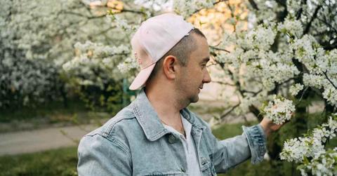 A man admiring a tree with white flowers blooming during springtime. (Representative Cover Image Source: Getty Images | Svetlana Repnitskaya)