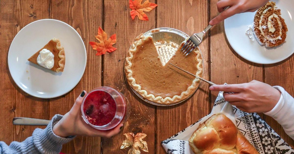 People cutting into a pumpkin pie with a cranberry cocktail. 