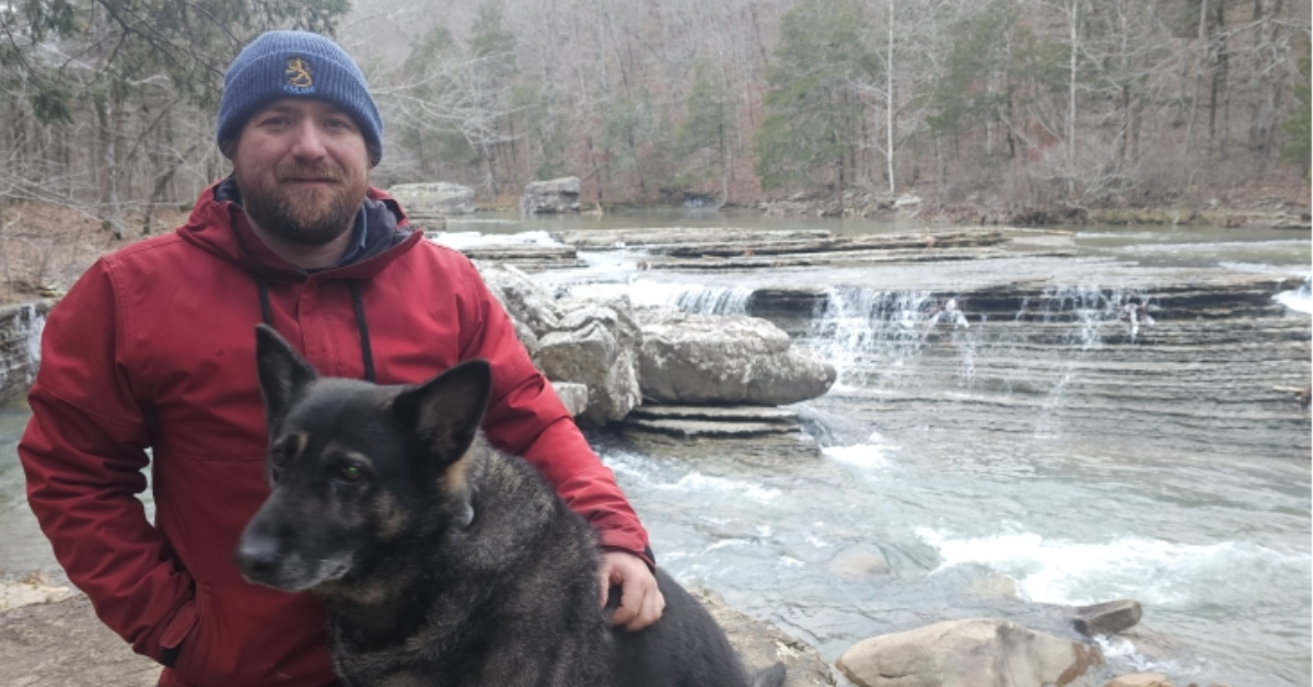 Chris Palmer and his dog Zoey pose in front of a river