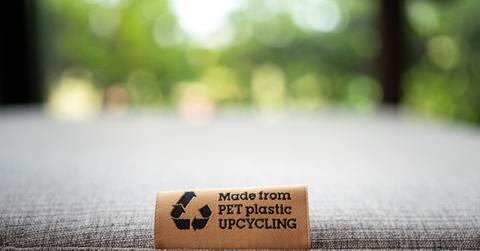 A "Made From PET Plastic Upcycling" product label tag is pictured on a sofa seat.