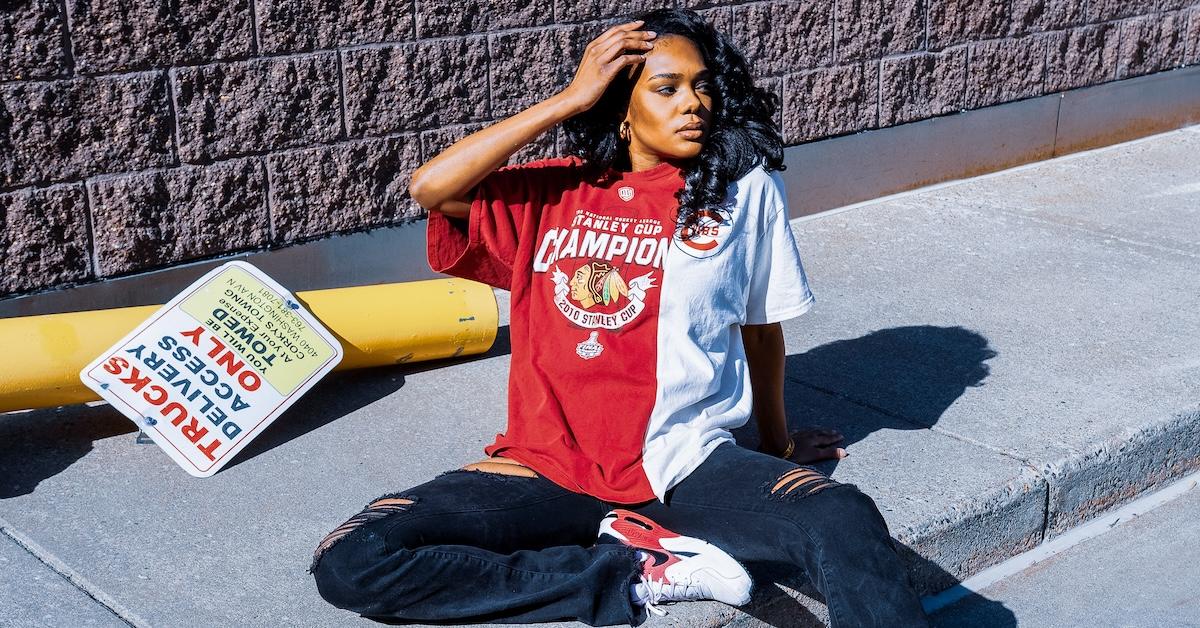 Woman wearing upcycled T-shirt models while sitting on a sidewalk