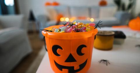 Traditional plastic, pumpkin trick-or-treating bucket filled with various gummy candy.