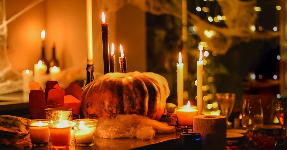 Halloween party decorations set up on a table, including a pumpkin and candles