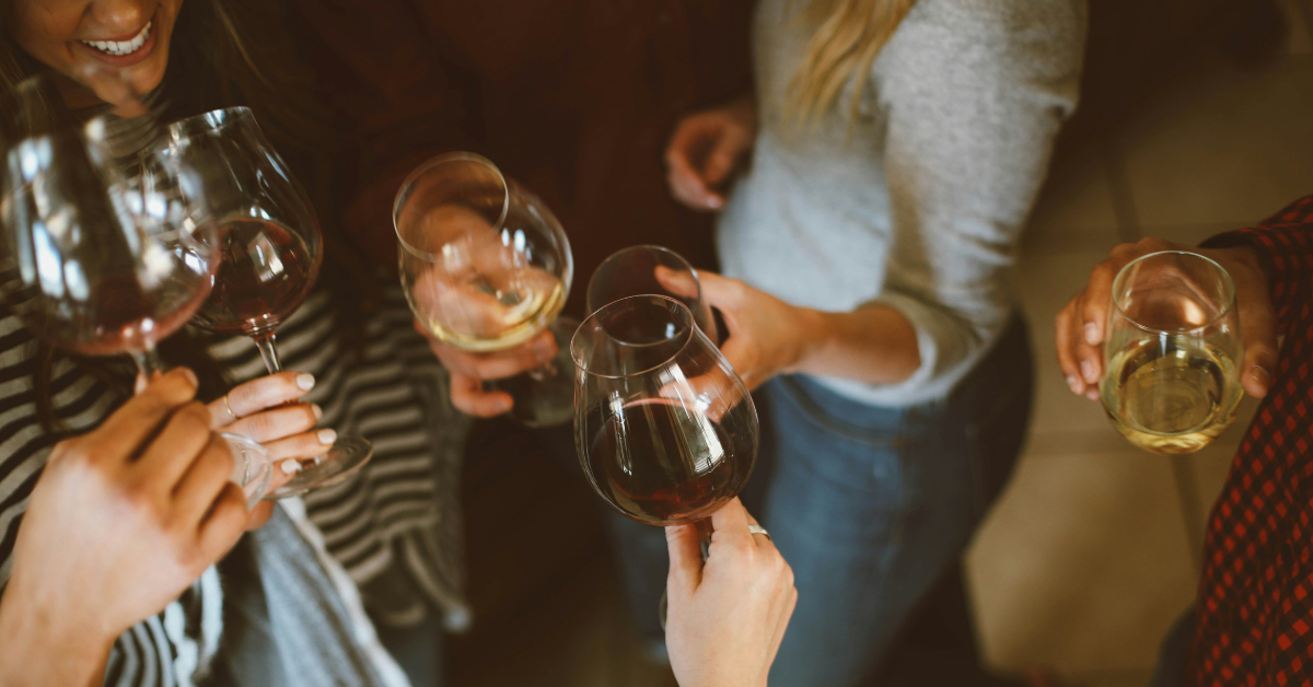 People hold up wine glasses filled with red or white wines