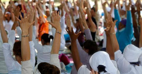 crowd doing yoga with hands raised