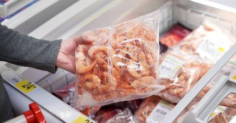 A frozen shrimp packet in hand at a grocery store (Representative Cover Image Source: Getty Images | sergeyryzhov)