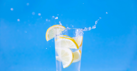 A lemon splashes into a glass of water