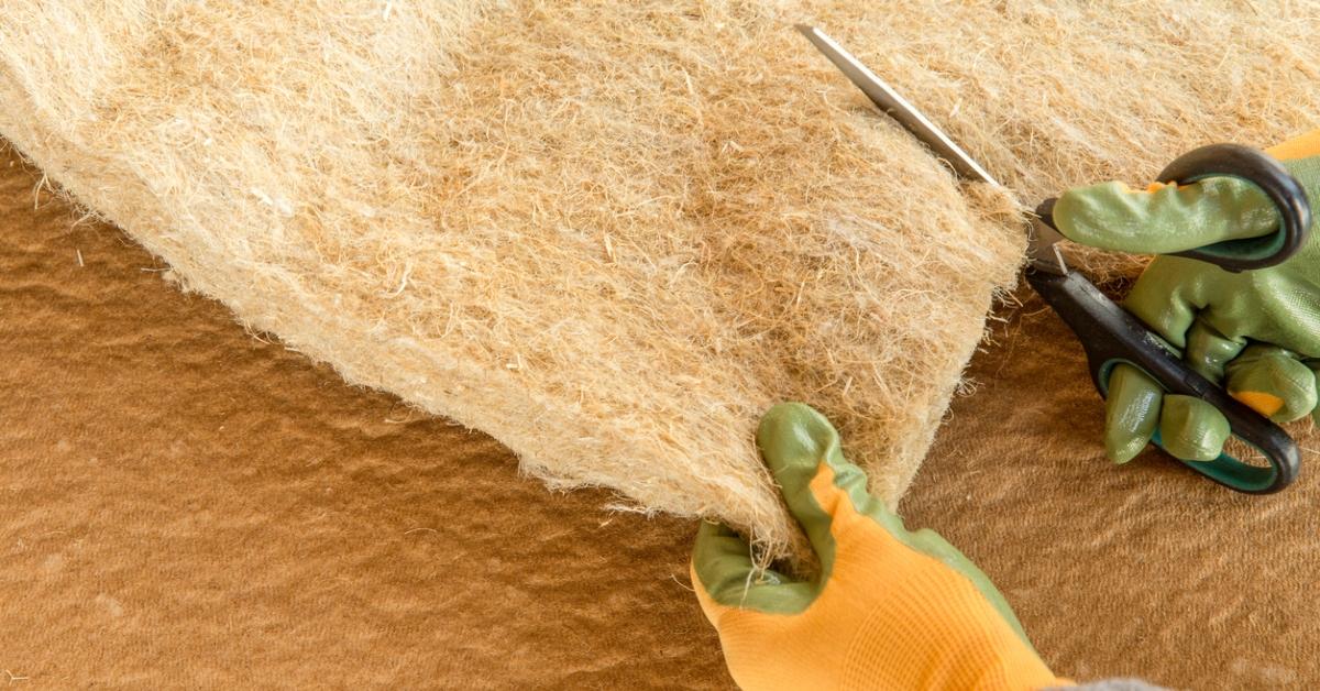 Close-up image of gloved hands cutting a hemp fabric covered panel