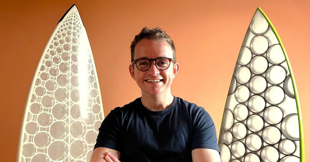 Man smiles in front of two Paradoxal Surfboards