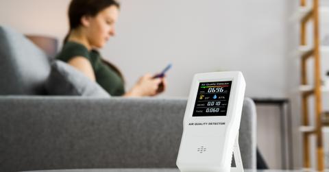 Woman on couch in background and particulate matter sensor in forground.