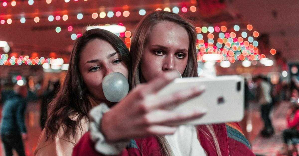 Two people pose for a selfie while blowing bubbles
