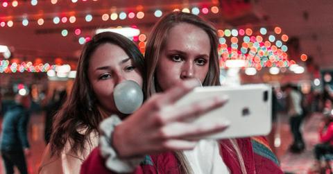Two people pose for a selfie while blowing bubbles