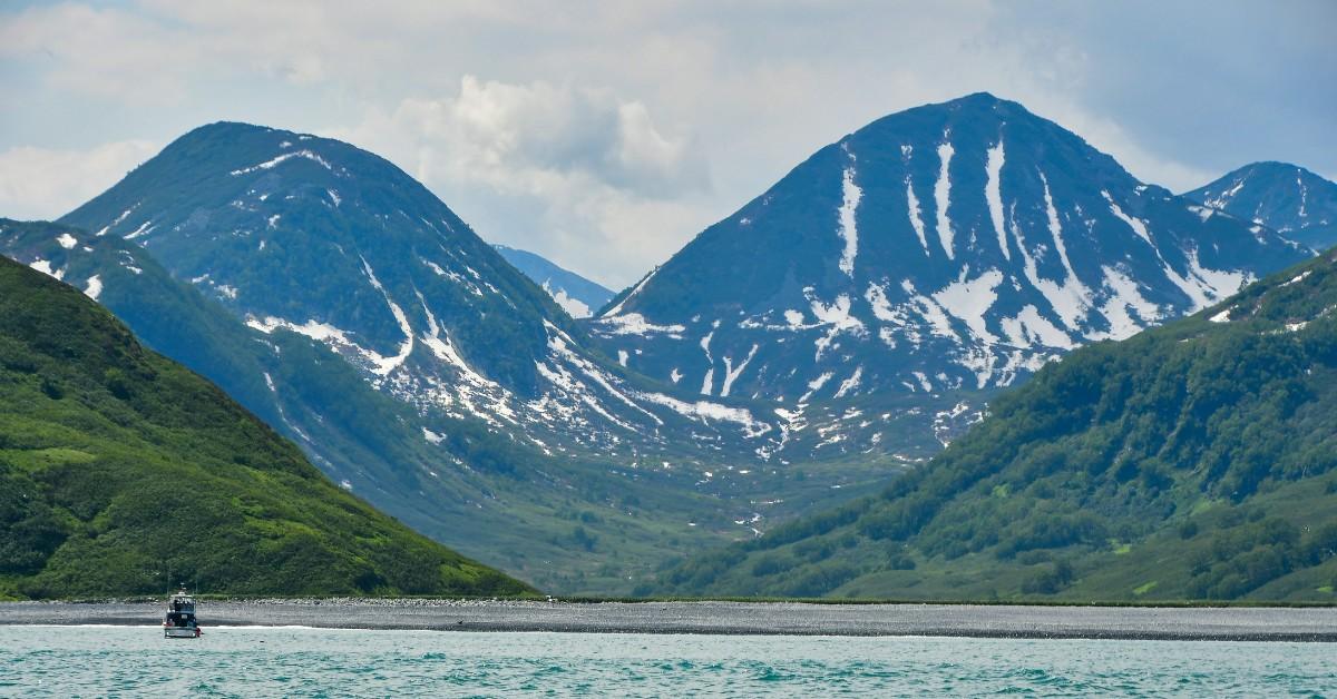A boat sails along the Kamchatka Peninsula which is home to the Klyuchevskaya volcano