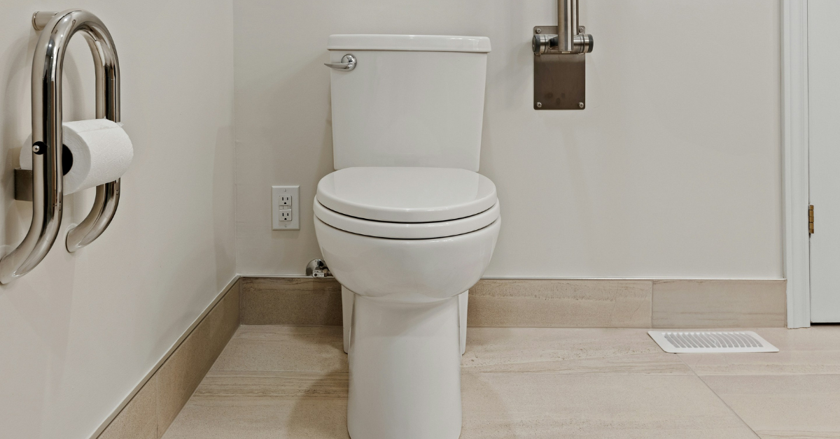 A white toilet seat with the lid down sits in a clean bathroom 