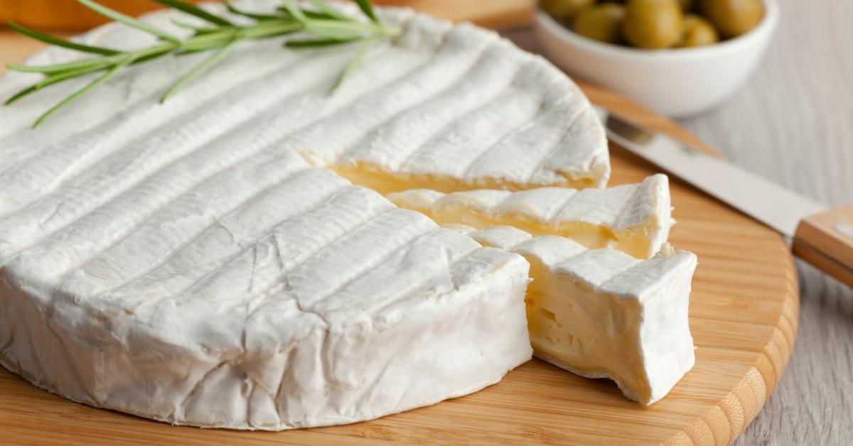 A photo of a wheel of French cheese with two slices cut out of it. 