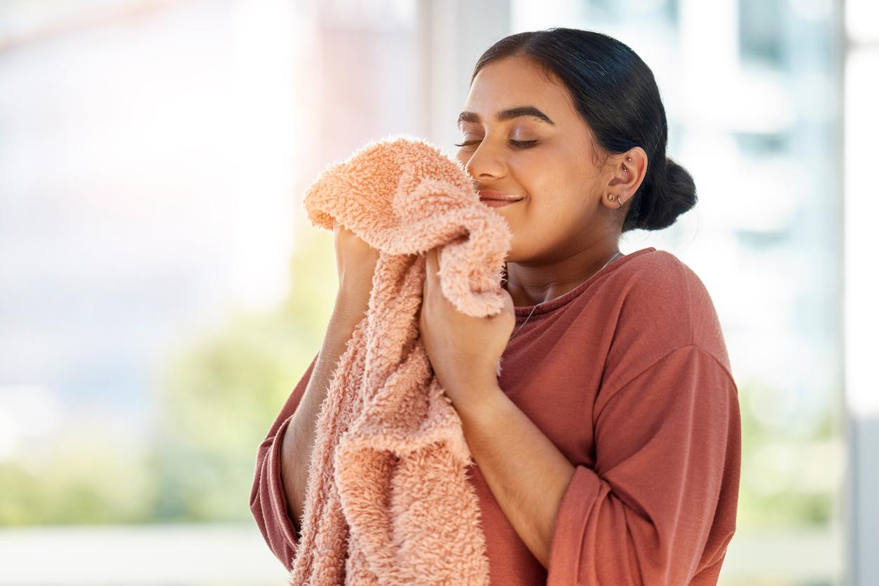 A smiling woman smells her freshly washed blanket using homemade laundry soap.