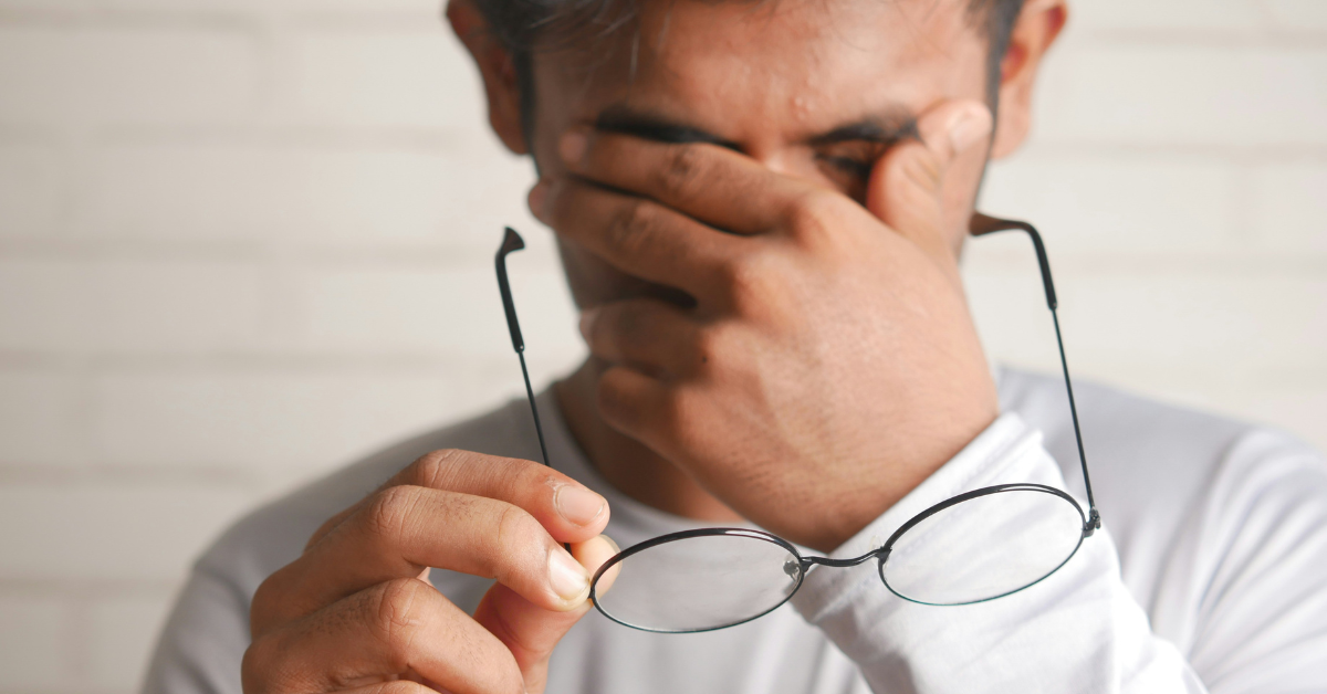 A man takes off his glasses and rubs his eyes