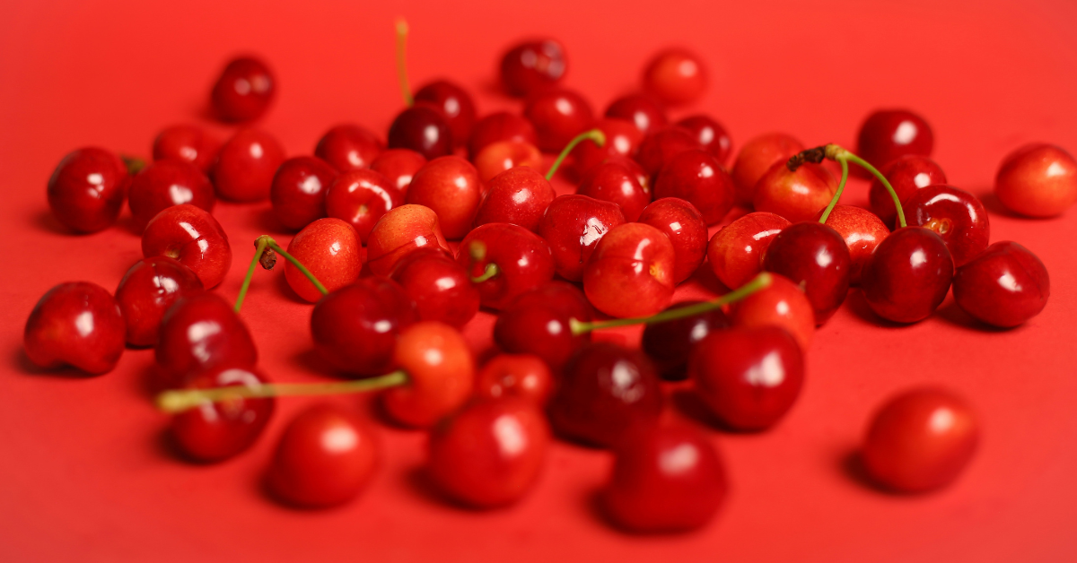 Red cherries are scattered on a red background