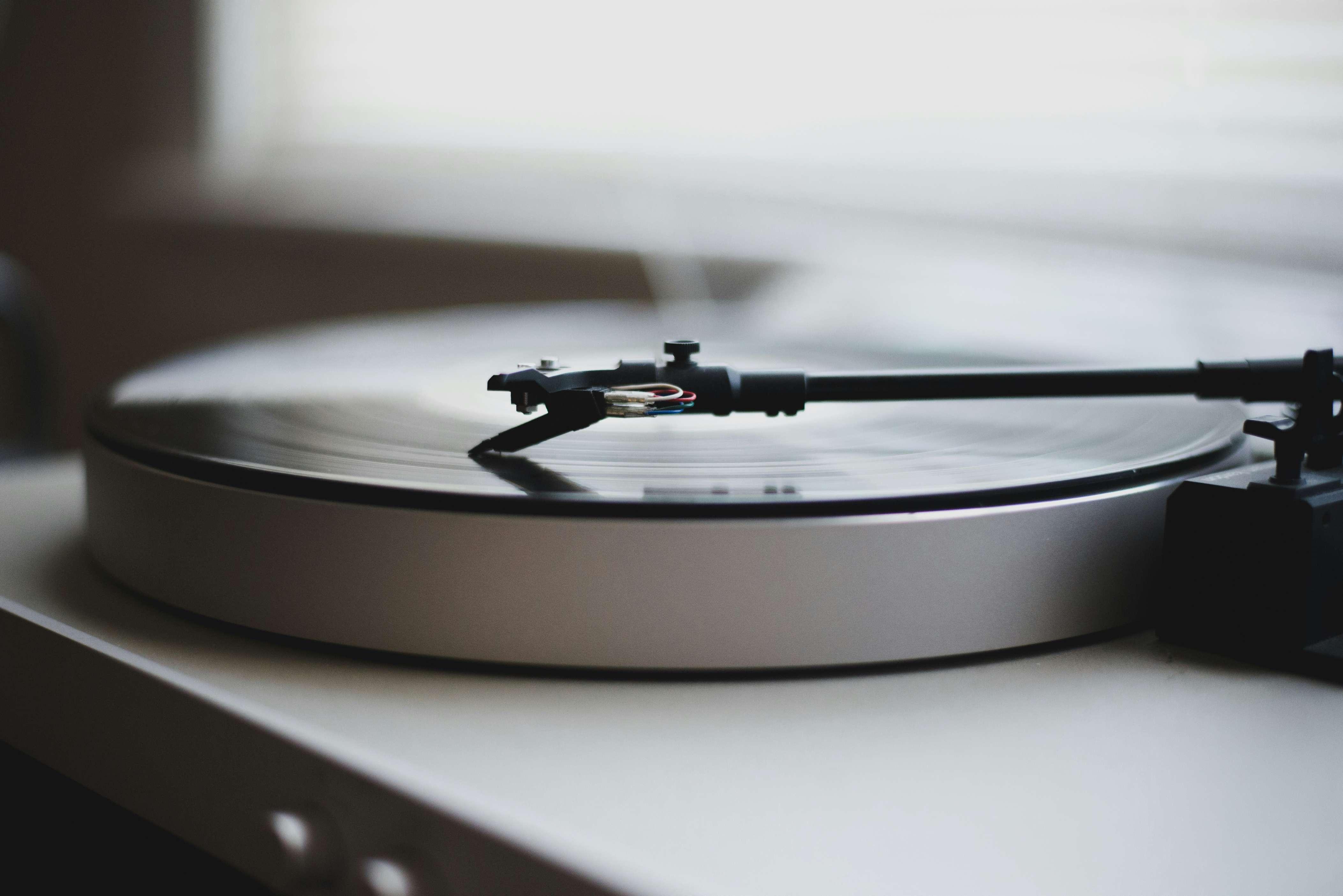 A record player is pictured with a vinyl record playing on top of it.