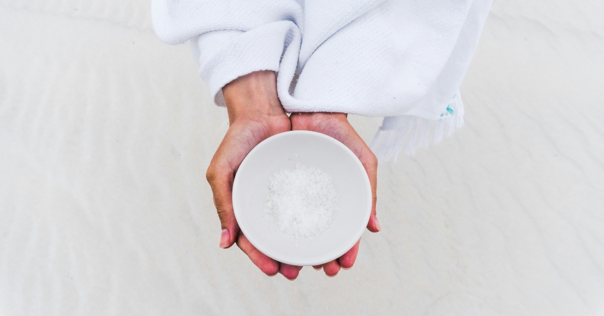 A woman cups a white bowl filled with salt crystals