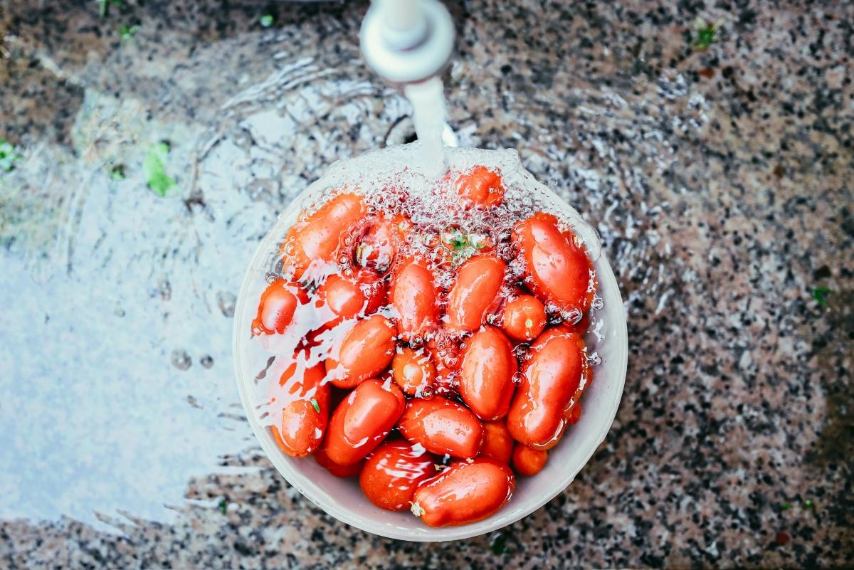 Running water on bowl of cherry tomatoes.