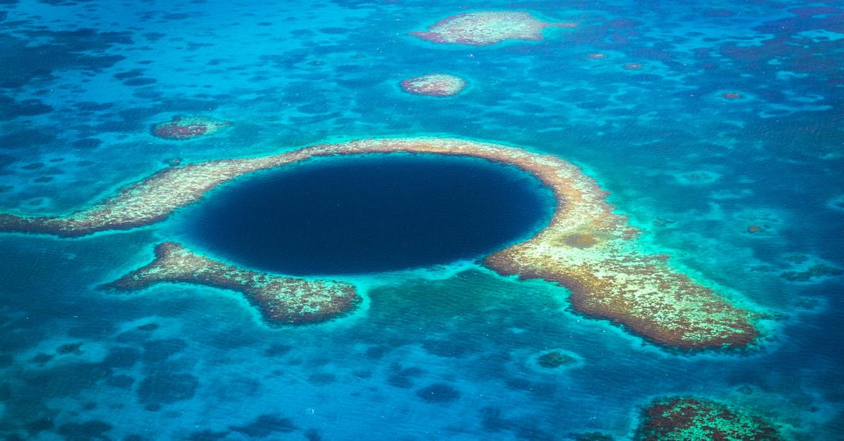 The blue hole in Belize appears as a dark blue hole in the lighter blue ocean.