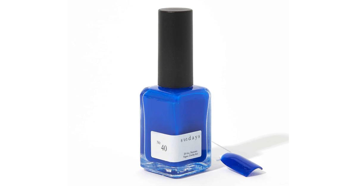 Cobalt blue Sundays nail polish with a fake nail beside it.