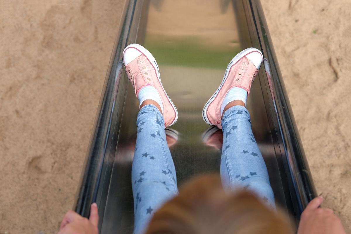 child's feet going down a metal playground slide