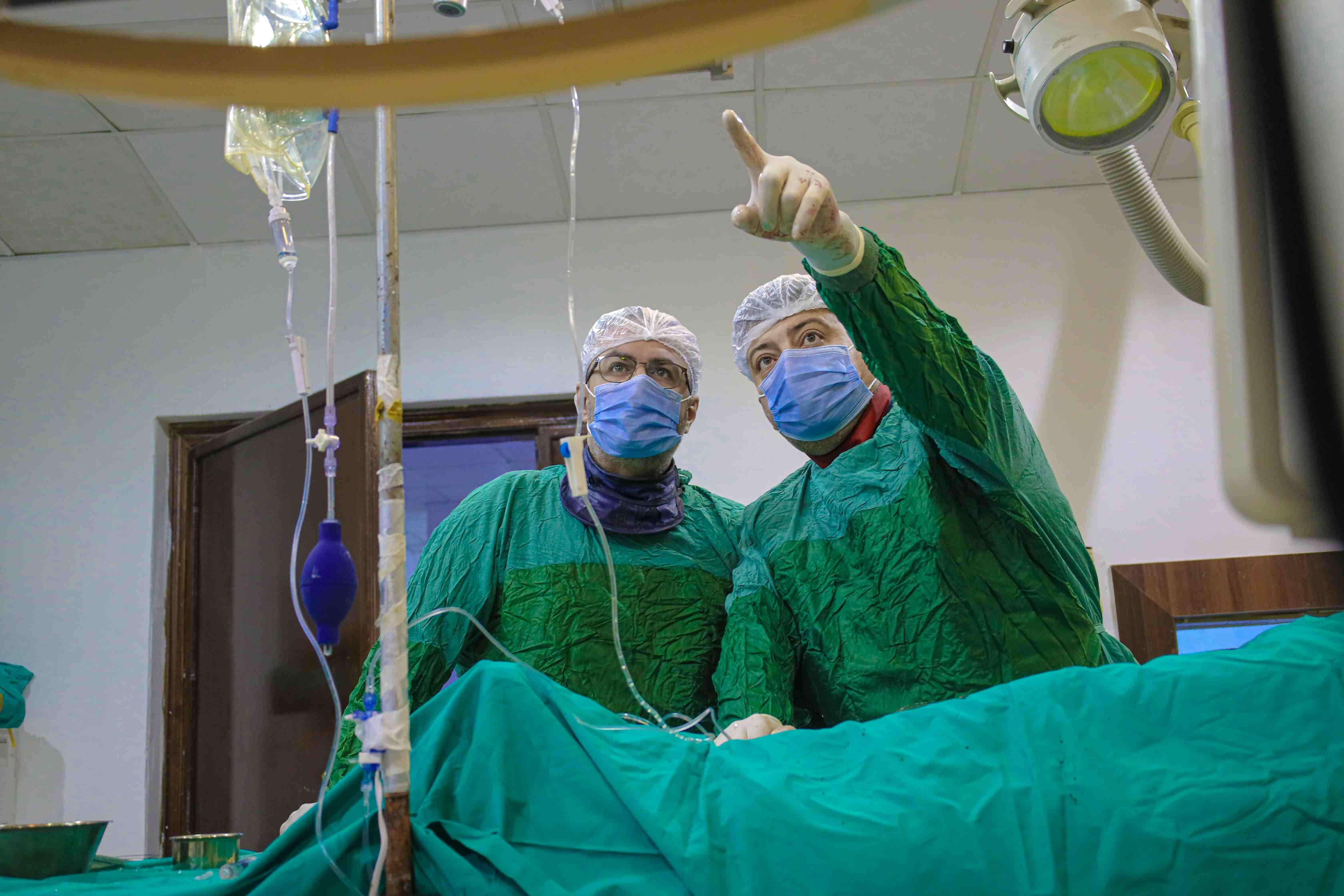 Two surgeons discuss a procedure while a patient lies on an operating table.