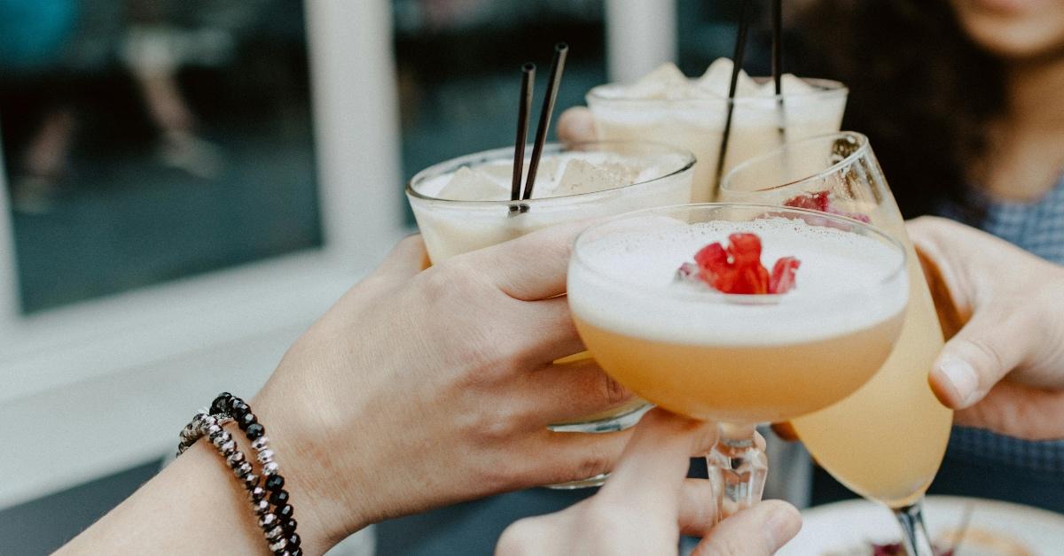 Four people clinking cocktail glasses together. 