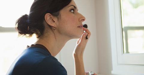 Woman applies makeup in a bathroom mirror