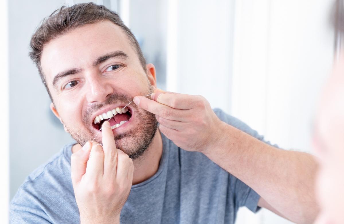 man flossing teeth