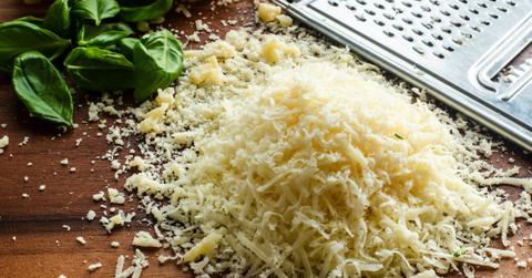 Shredded cheese sits piled up next to a cheese grater