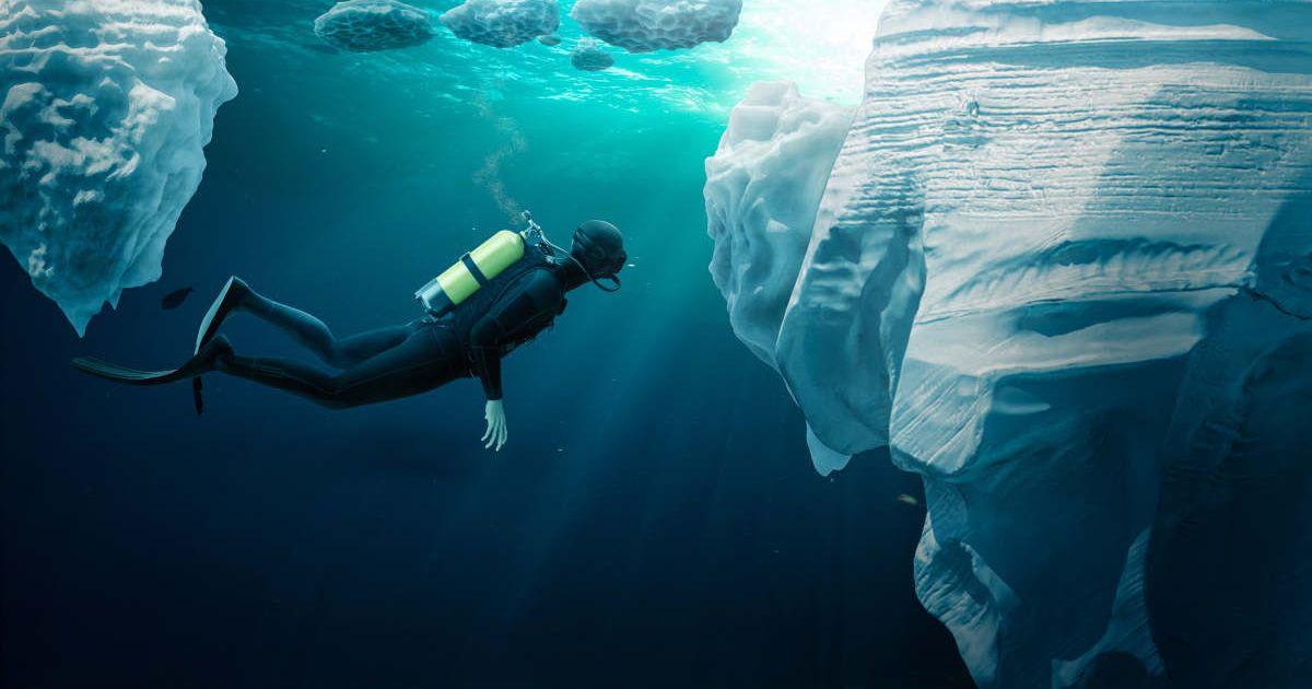 Diver inside icy cool waters swimming in front of a gigantic iceberg (Representative Cover Image Source: Getty Images | S_Bachstroem)