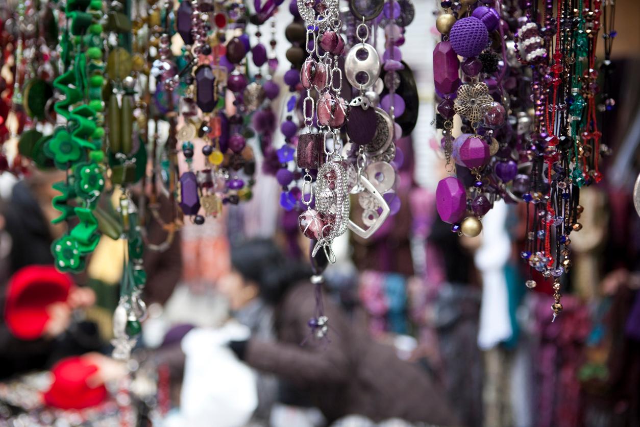 An outdoor jewelry store at a market in Spain displays various necklaces available for sale.