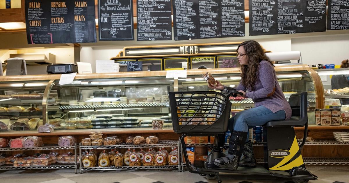 Woman uses mobility scooter in a deli.