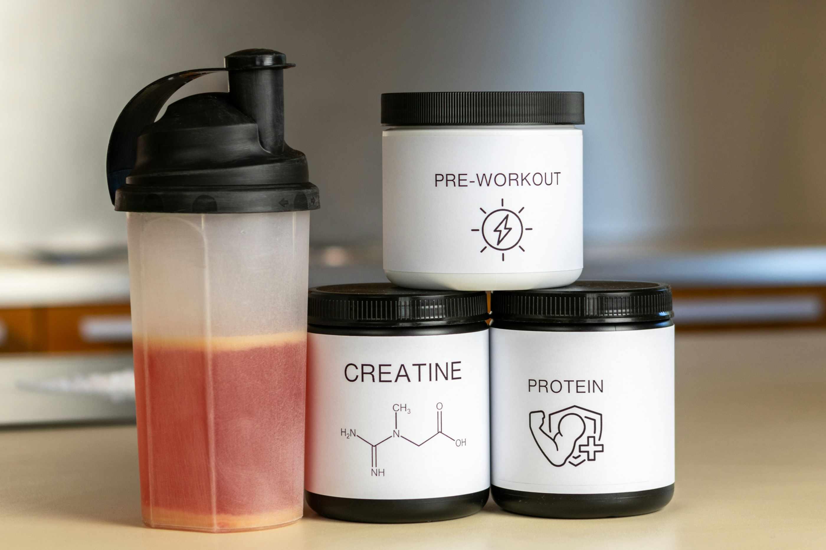 Bottles of creatine, protein, and pre-workout are pictured beside a shaker bottle.