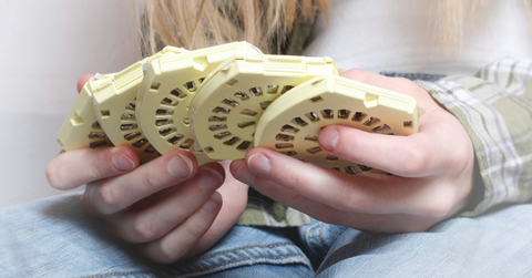 A woman holds five yellow birth control pill packs
