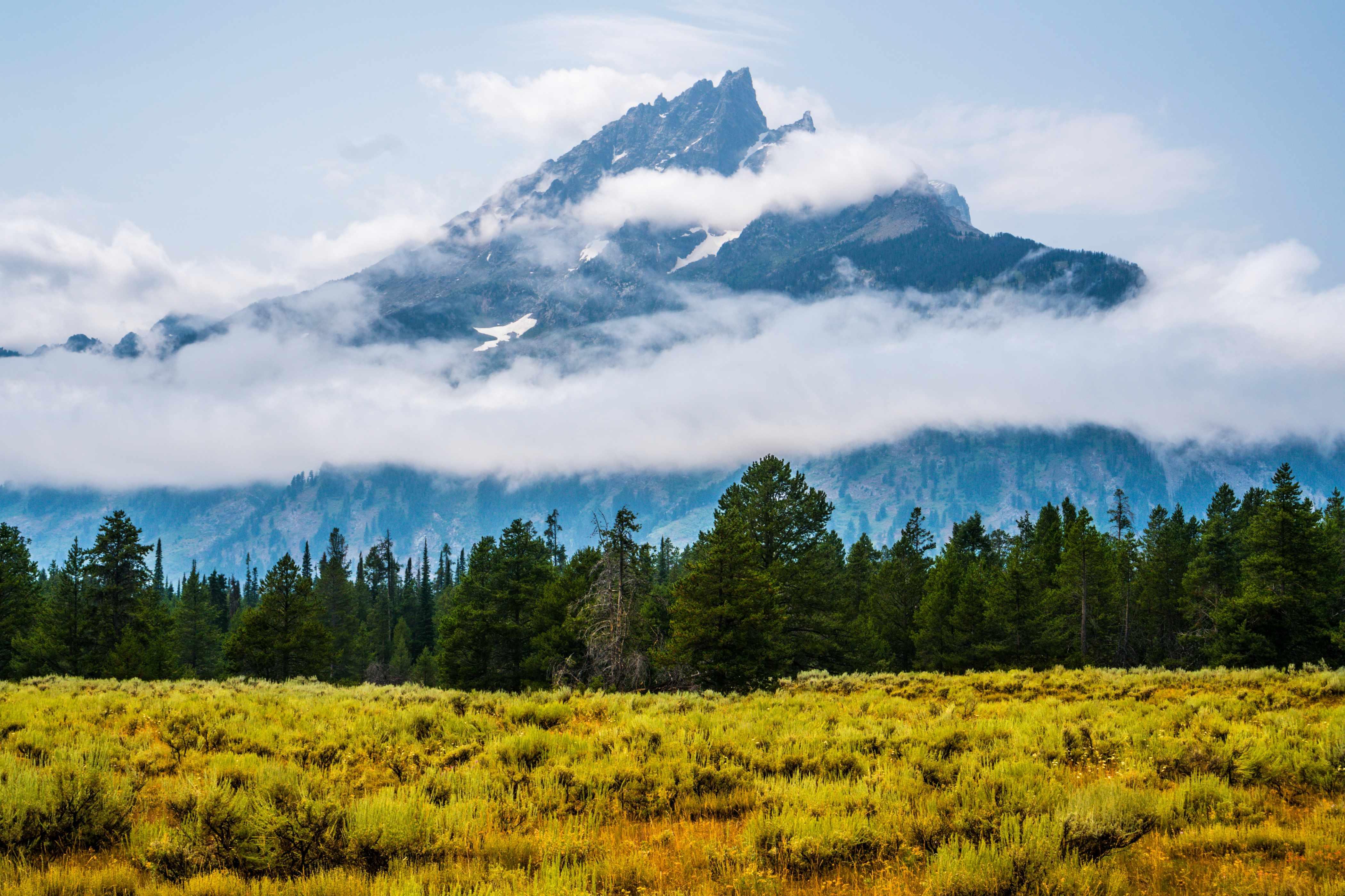 Yellowstone National Park is pictured with cloudy skies surrounding mountains.