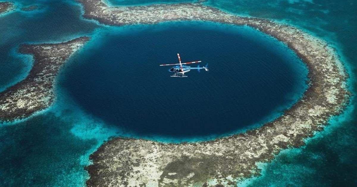 A helicopter flying over The Great Blue Hole. (Representative Cover Image Source: Pixabay | Photo by xiSerge)
