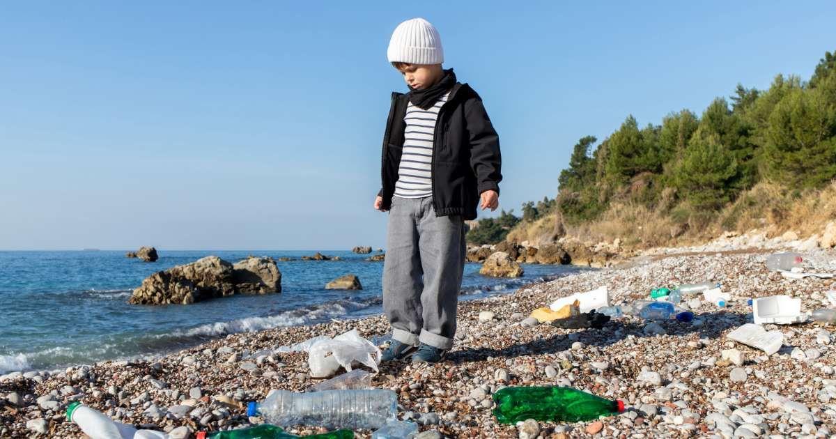 A little boy is disappointedly looking at the plastic pollution on a beach. (Representative Cover Image Source: Getty Images | Tatiana Cheremukhina)
