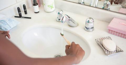 Person wetting a toothbrush before brushing.
