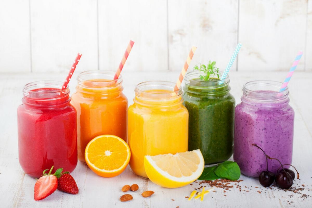 Five brightly-colored smoothies in clear glass jars