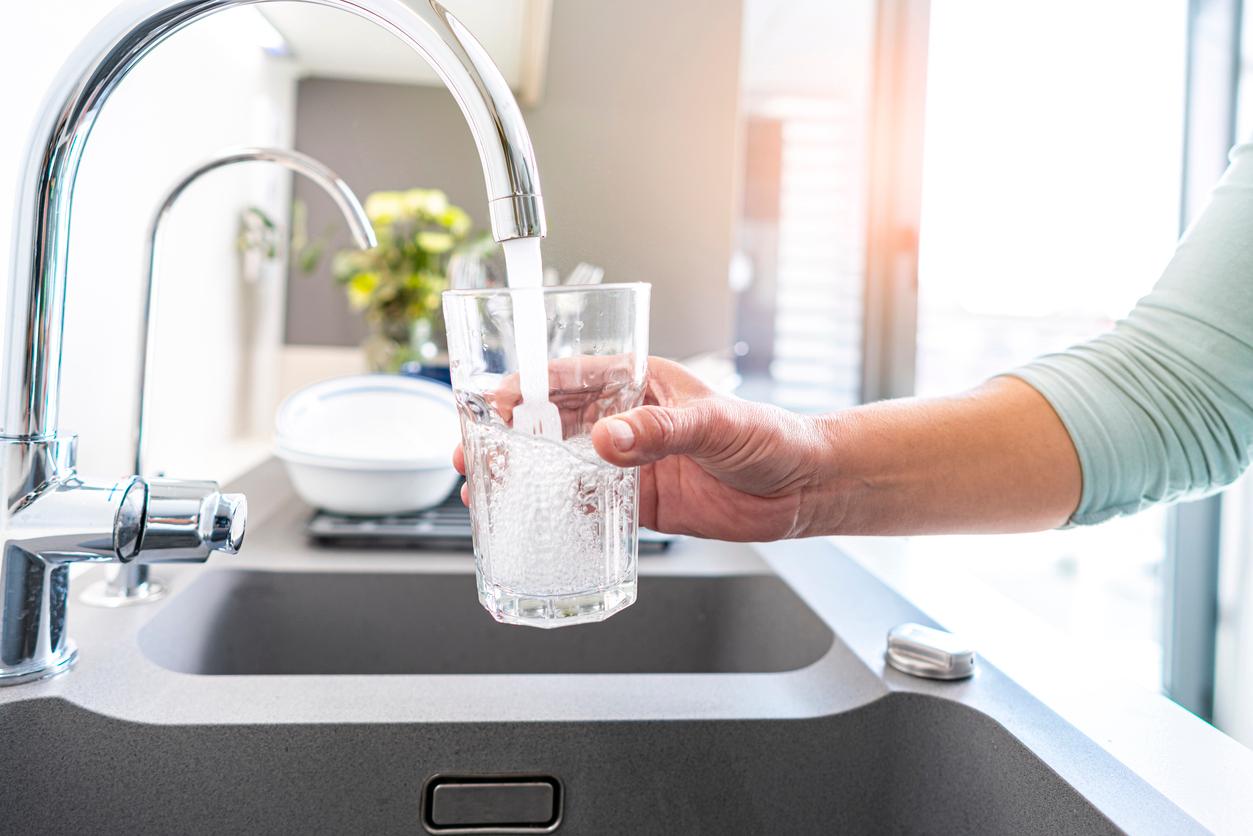 A faucet pouring water into a glass. 