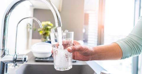 A faucet pouring water into a glass.