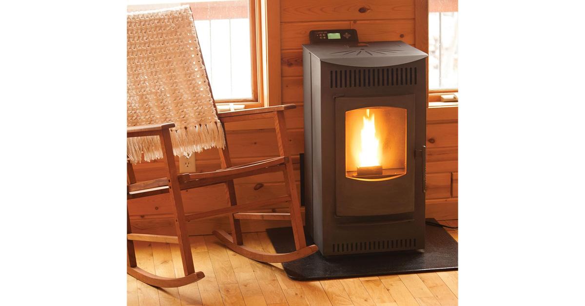 pellet stove with a fire inside on a wood floor with wooden rocking chair and crocheted blanket